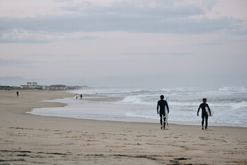 Fototapeta na wymiar Surfers walking on the beach in the morning