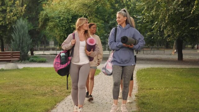 Positive multinational mature women going to yoga and talking outdoors