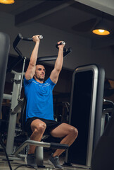 young man exercising lats on machine