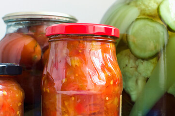 Home made preserves on neutral background. Homemade tomato sauce and canned vegetables, close-up.