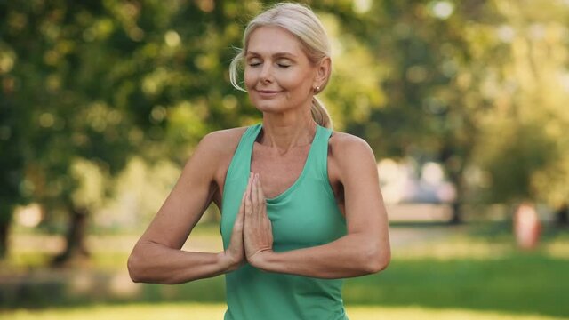 Positive mature woman meditating outdoors