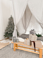 Christmas decorated rustic wooden bedroom interior in gray, white, silver colours with big baldaquin bed, fake fur blanket, candles, Christmas fir tree and gifts on floor. Christmas morning  © somegirl