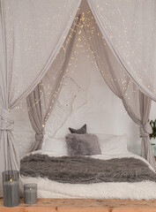 Christmas decorated rustic wooden bedroom interior in gray, white, silver colours with big baldaquin bed, fake fur blanket, candles, Christmas fir tree and gifts on floor. Christmas morning  © somegirl