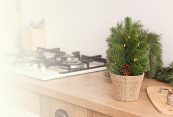 Little Christmas tree and metal cookie molds on cutting board next to kitchen stove, baking background in bright decorated festive interior, space for text