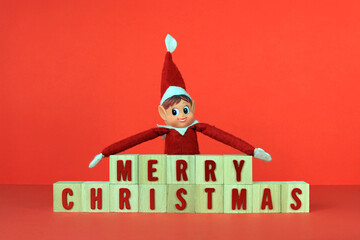 Christmas elf with a message merry Christmas written on wooden cubes
