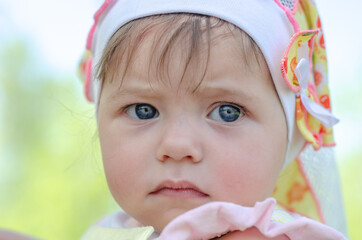 Portrait of an upset one-year-old baby with gray-blue eyes close-up