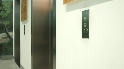 Business man pushing red button for calling elevator in modern business office. Business manager coming into elevator in modern apartment corridor.