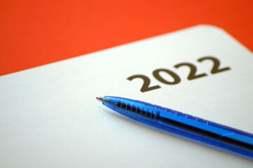 the blue pen lies on a blank sheet of notepad for the new year 2022