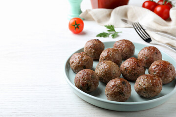 Tasty cooked meatballs served on white wooden table. Space for text