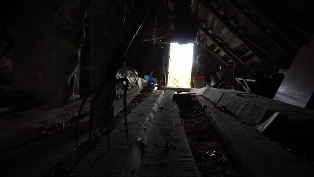 Man walks with pitchfork in a dark attic towards the exit, killer with pitchfork, horror shot for halloween, horror movie