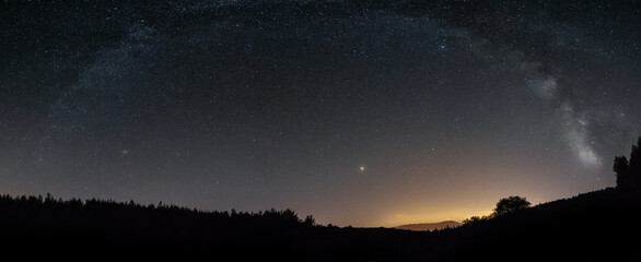 Milky Way arc on the top of the mountain and with the lights of Portugal behind