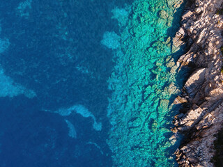 Fototapeta na wymiar Top view of transparent shallow turquoise ocean sea water surface and rock. Aerial top view, Aquamarine background