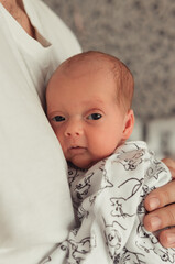Close-up portrait of newborn baby laying tight on father's chest. Father holding tight newborn daughter in his arms. Selective focus. Film grain
