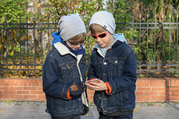 bracia chłopcy z telefonem komórką w ręce jesień - obrazy, fototapety, plakaty