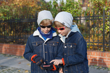 bracia chłopcy z telefonem komórką w ręce jesień