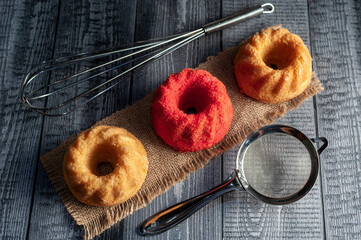 vanilla and red velvet puddings with powdered sugar with strainer and whisk on wooden table and...