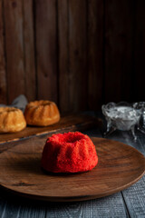 vanilla and red velvet puddings with powdered sugar with strainer and whisk on wooden table and plate and window light