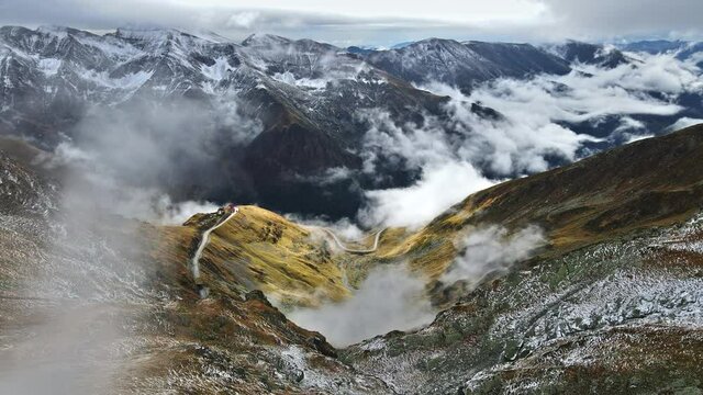 Aerial drone view of nature in Romania. Transfagarasan route in Carpathian mountains, snow on mountains rocky slopes, valley, clouds