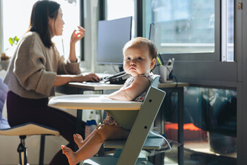Adorable Girl Sitting On High Chair Near Mother