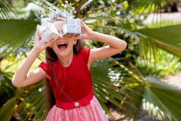Litle girl closes her eyes with gift boxes and laughs.