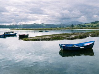 Fototapeta na wymiar Paisaje de San Vicente de la Barquera con barcas en el agua, en Cantabria, España, en el verano de 2020.
