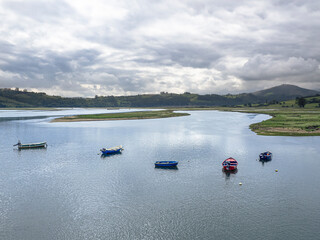 Paisaje de San Vicente de la Barquera con barcas en el agua,  y el reflejo de las nubes y monta&ntilde;as al fondo, en Cantabria, Espa&ntilde;a, en el verano de 2020.