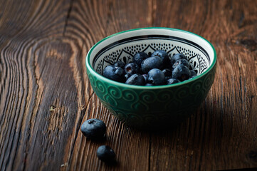Blueberries in dark setting on wooden backround. Blueberries fruit background.Fresh blueberry in ceramic spoon.
