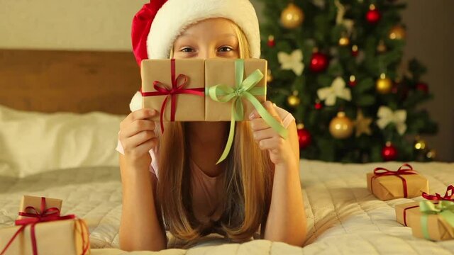 child at home in an interior decorated for Christmas opens holiday gifts 