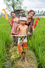 Balinese young girl and boy in rice fields in traditional dress and with flags. 