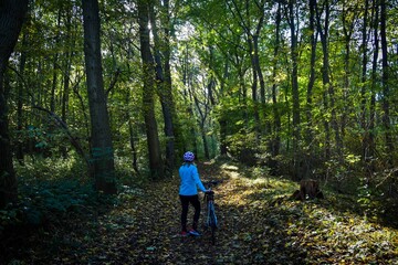 Obraz premium Frau mit dem Rad fährt durch den Wald