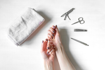 Closeup of woman hands with polished nails and manicure instruments. caucasian woman receiving french manicure at home or at nail salon. manicure, selfcare, beauty procedures yourself