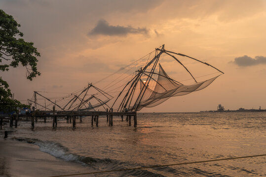 View of the typical Chinese nest on the beach in Kochi at sunset, Kerala region, India.