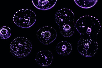 Glowing drops of transparent liquid on a black background. Drops gel or oil close up. Abstract pattern.
