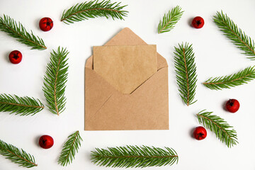 Closeup eco craft envelope, letter to Santa. Frame of fir branch or spruce branch and red berries isolated on white background. Fir tree branches. Christmas greeting card. Template for design