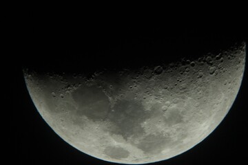 Moon close up seen through a telescope. Visible craters and furrows on the surface.