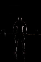 Fototapeta na wymiar Athlete lifting barbell. Silhouette of a muscular man