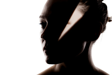 Fashionable studio portrait of a cute girl. Silhouette of a beautiful young woman with hard shadows on her face against white backgroung.