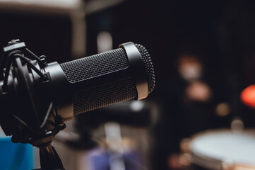 Condenser microphone, with a blurred rehearsal room in the background and a copy space to the right