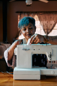 Woman with one hand working on a sewing machine