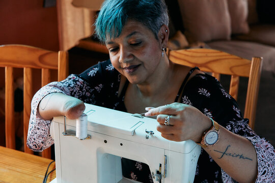 Woman with one hand working on a sewing machine