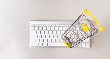 Overhead view of a miniature shopping cart on a computer keyboard on gray background with copy space - Powered by Adobe