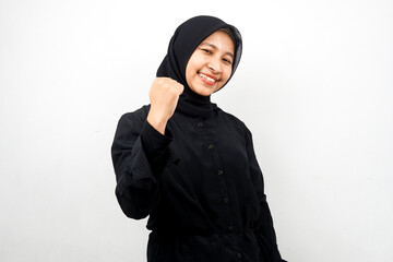 Beautiful young asian muslim woman smiling confident, enthusiastic and cheerful with hands clenched, sign of success, punching, fighting, not afraid, victory, isolated on white background