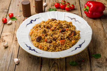 pilaf with beef on plate on wooden table