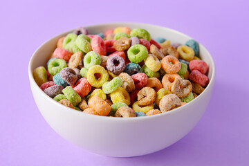 Bowl with crunchy corn flakes rings on color background