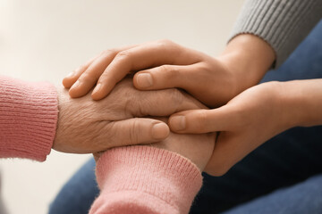 Young woman holding hands of grandmother at home, closeup - obrazy, fototapety, plakaty