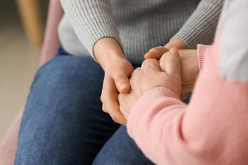 Young woman holding hands of grandmother at home