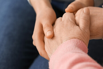 Young woman holding hands of grandmother, closeup