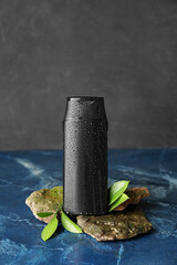 Bottle of shower gel with water drops and stones on table