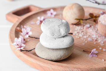 Fototapeta na wymiar Tray with spa stones with blossoming branch on white background, closeup