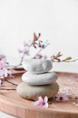 Tray with spa stones with blossoming branch on white background, closeup